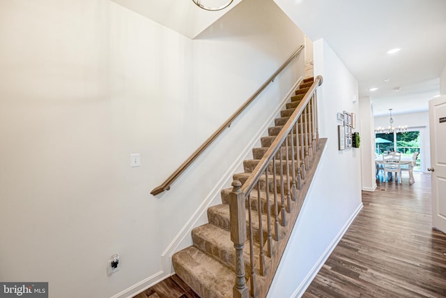 stairs with a notable chandelier, baseboards, wood finished floors, and recessed lighting