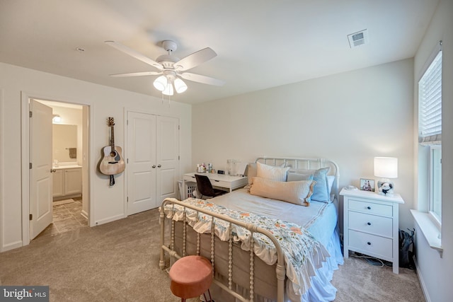 carpeted bedroom featuring a closet, visible vents, ensuite bathroom, a ceiling fan, and baseboards