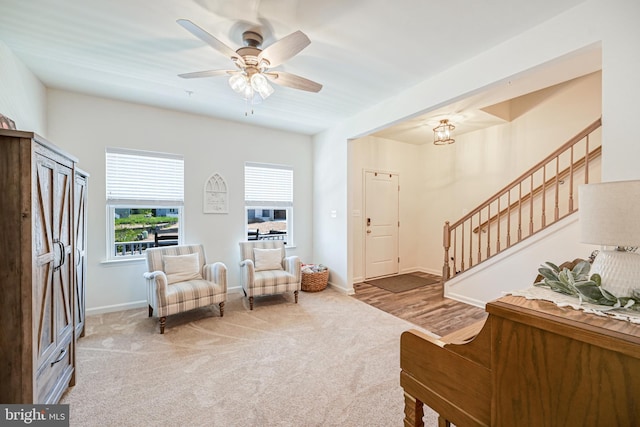 sitting room featuring stairway, carpet flooring, a ceiling fan, and baseboards