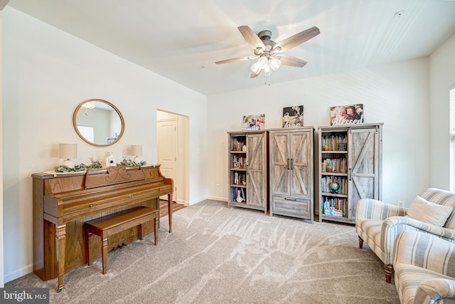 living area with light carpet, ceiling fan, and baseboards