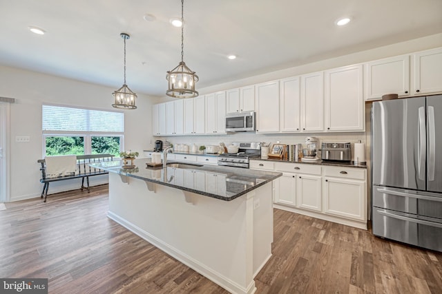 kitchen with wood finished floors, appliances with stainless steel finishes, a sink, and decorative backsplash