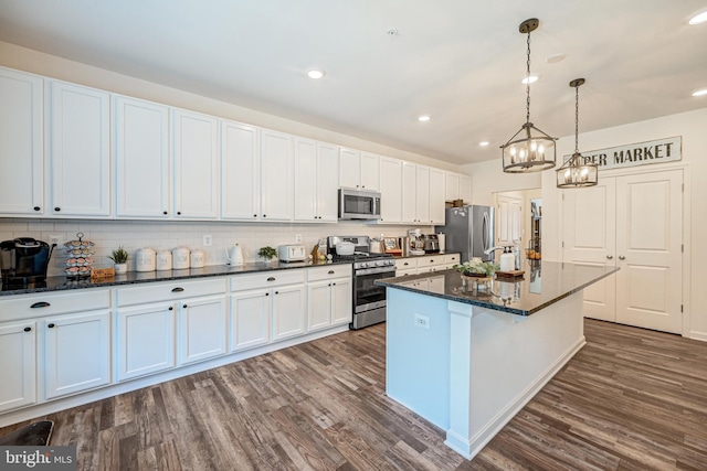 kitchen featuring decorative backsplash, appliances with stainless steel finishes, dark wood-type flooring, a center island, and white cabinetry