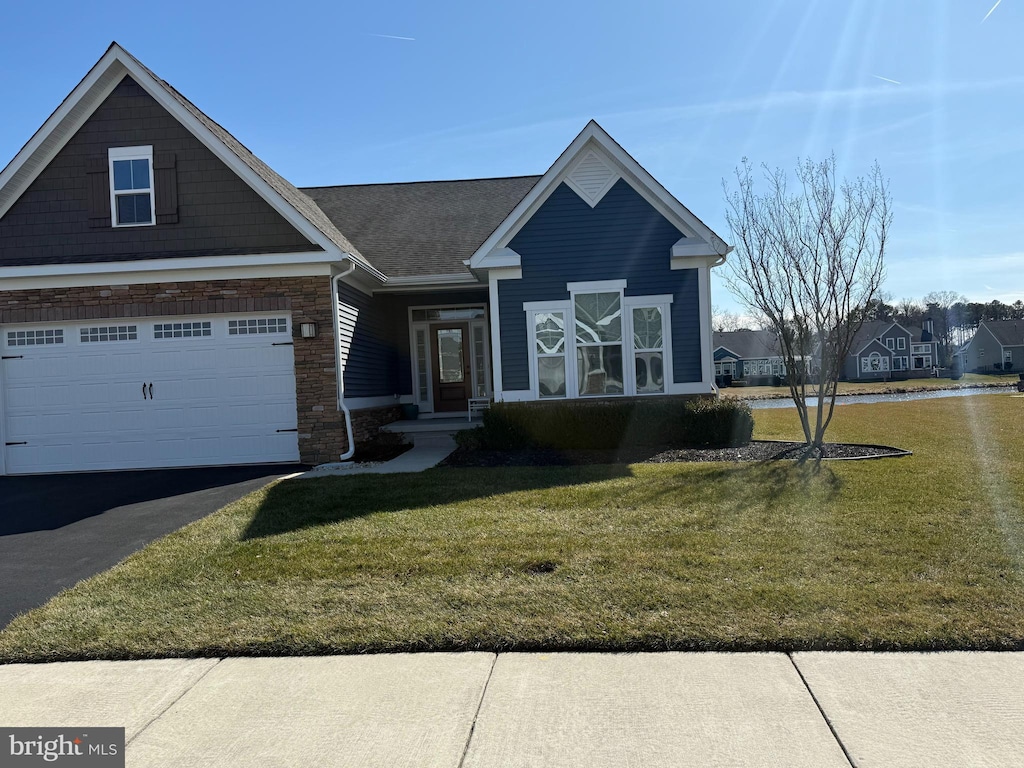 view of front of home featuring driveway, brick siding, and a front yard