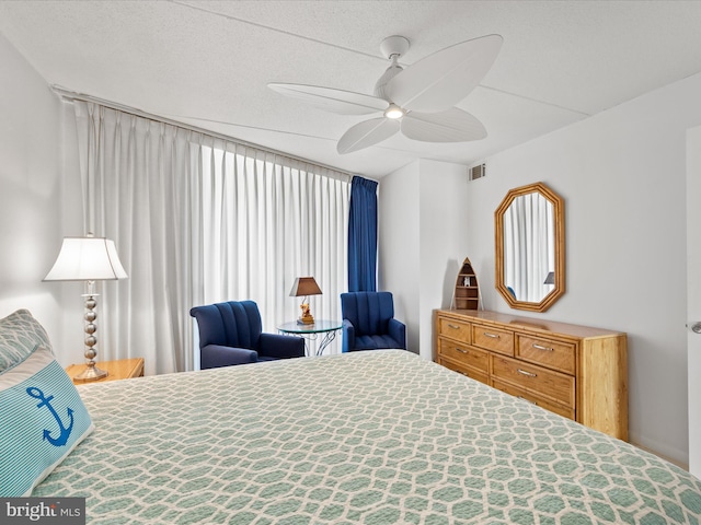 bedroom with a ceiling fan, visible vents, and a textured ceiling