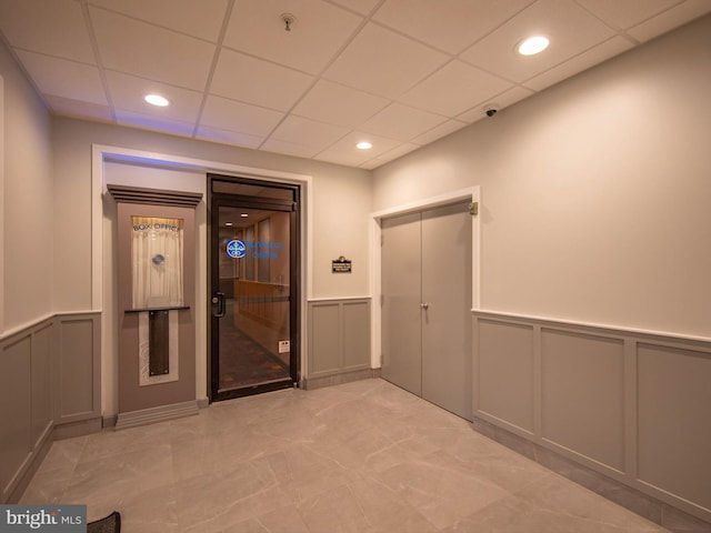 hallway with recessed lighting, wainscoting, a decorative wall, and a drop ceiling