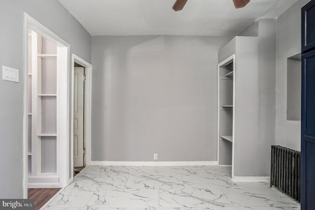 spacious closet featuring radiator, marble finish floor, and ceiling fan