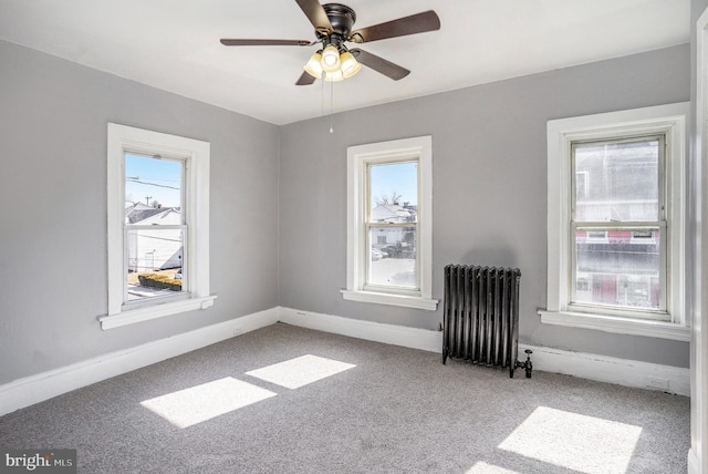 carpeted spare room featuring radiator heating unit, baseboards, plenty of natural light, and ceiling fan