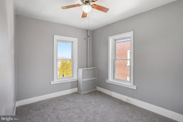 carpeted spare room with baseboards and a ceiling fan