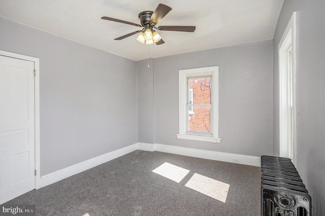 carpeted spare room with radiator, a ceiling fan, and baseboards