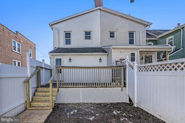 back of property with stairway, a chimney, a deck, and fence