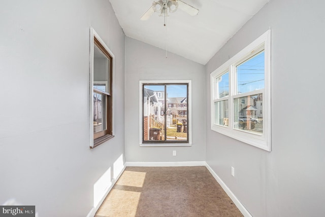 empty room featuring carpet flooring, ceiling fan, baseboards, and lofted ceiling