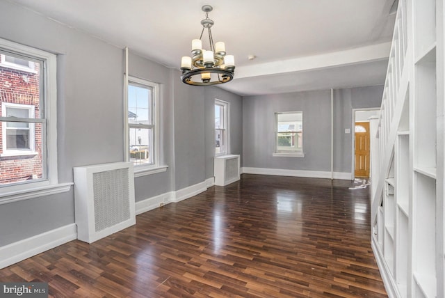 unfurnished dining area featuring a chandelier, baseboards, and wood finished floors