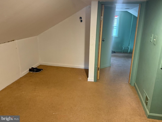 bonus room with vaulted ceiling and light colored carpet