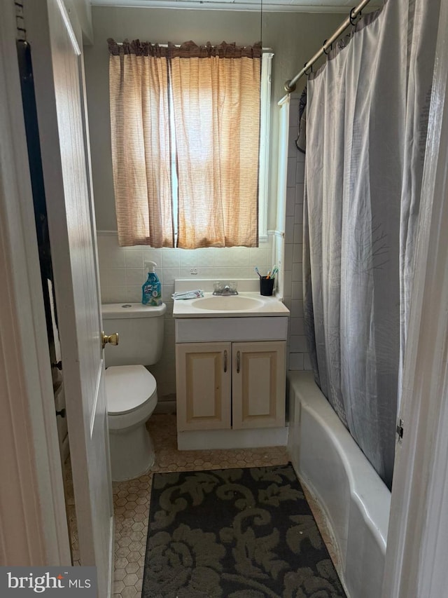 full bathroom with shower / tub combo with curtain, vanity, tile walls, and toilet