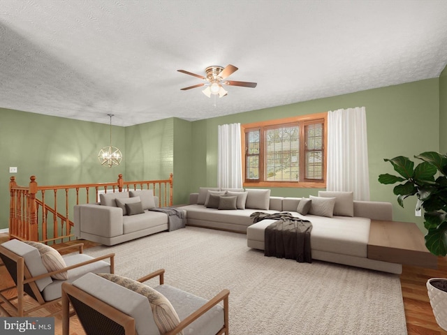 living room featuring ceiling fan with notable chandelier, a textured ceiling, and wood finished floors