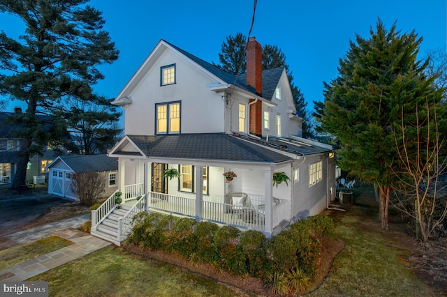 view of front of home with central AC unit, a chimney, roof with shingles, a porch, and stucco siding