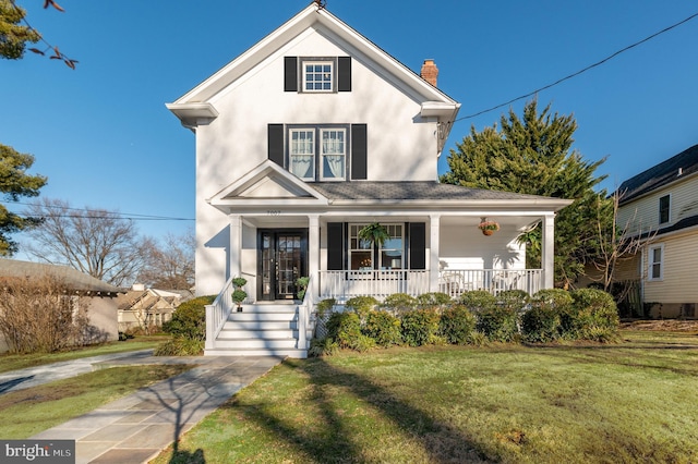 view of front of house with a porch, a chimney, a front yard, and stucco siding