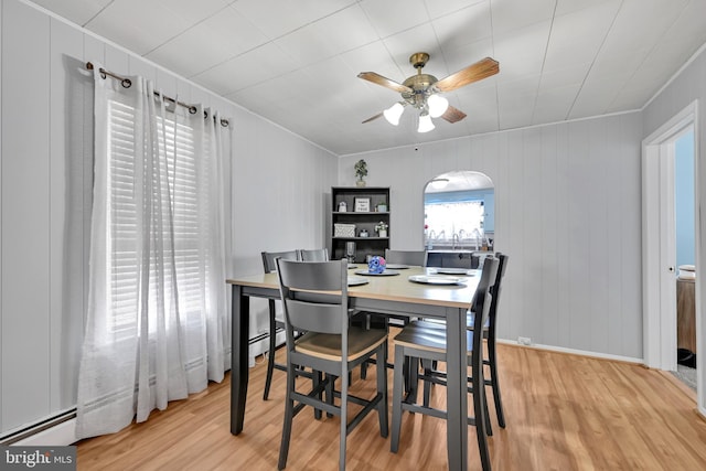 dining room with a ceiling fan, arched walkways, light wood-style flooring, and baseboard heating