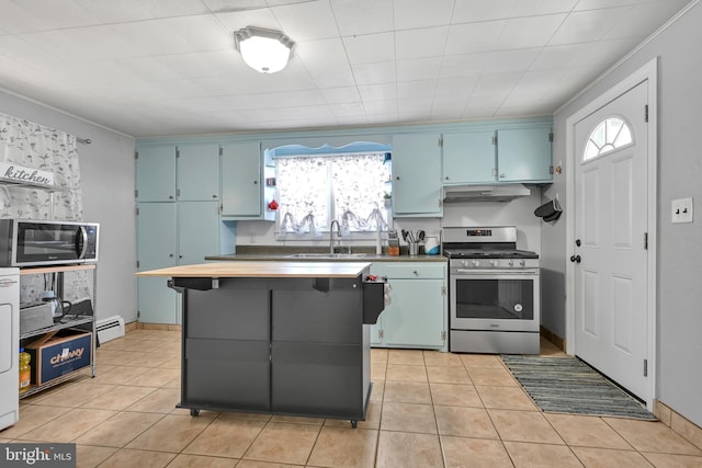 kitchen featuring blue cabinetry, light tile patterned floors, stainless steel appliances, a sink, and under cabinet range hood