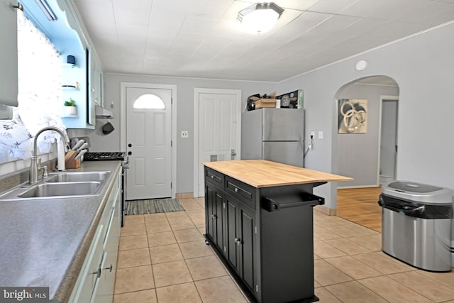 kitchen with gas range, wood counters, freestanding refrigerator, dark cabinetry, and a sink