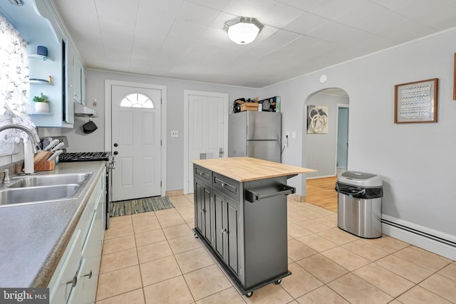 kitchen with arched walkways, gray cabinets, wooden counters, appliances with stainless steel finishes, and a sink