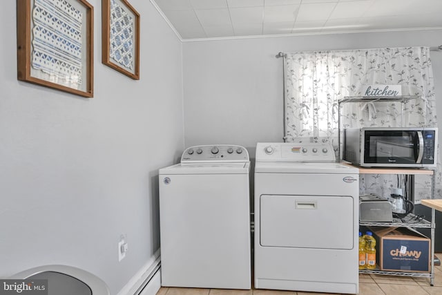 laundry area with laundry area, light tile patterned floors, ornamental molding, washing machine and dryer, and a baseboard heating unit