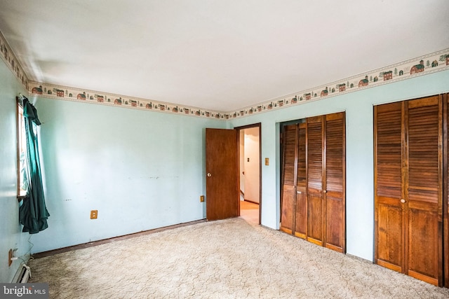 unfurnished bedroom featuring carpet floors and two closets