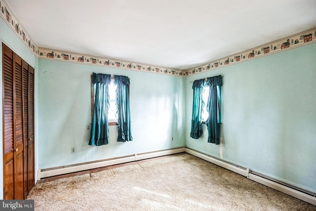 carpeted empty room featuring a baseboard radiator