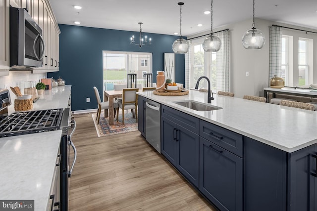 kitchen featuring hanging light fixtures, blue cabinetry, stainless steel appliances, and sink