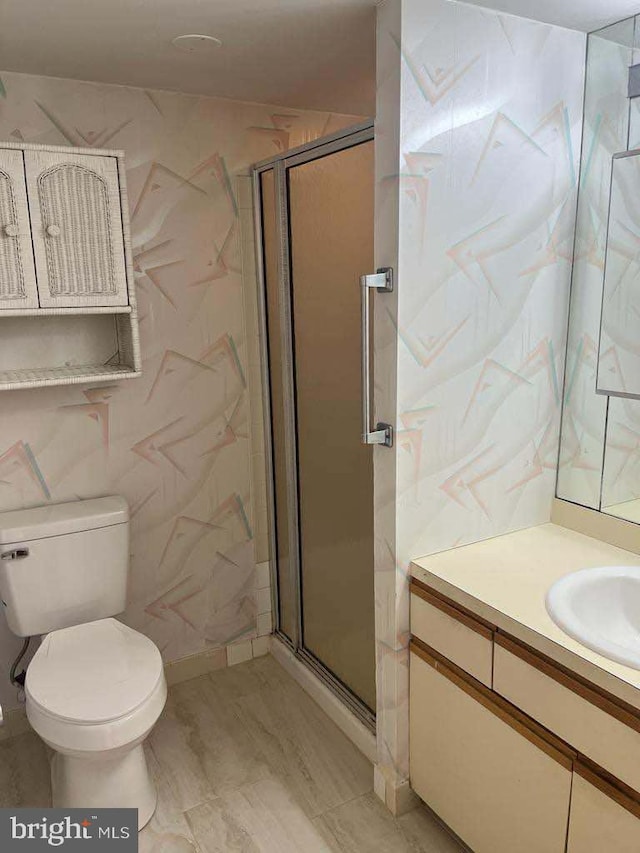 bathroom with toilet, a shower with door, and vanity