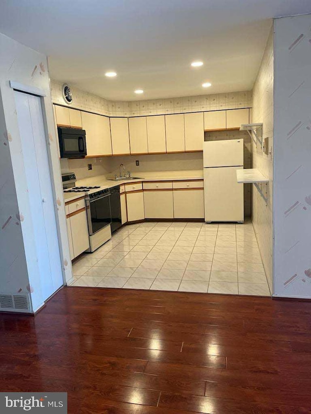 kitchen with sink, black appliances, and light hardwood / wood-style flooring