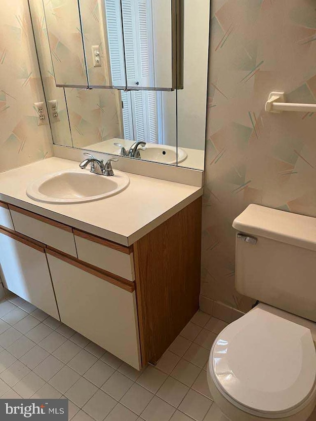 bathroom with toilet, vanity, and tile patterned flooring