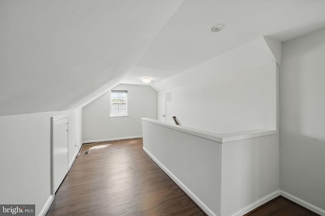 bonus room with dark wood-style flooring, baseboards, visible vents, and lofted ceiling