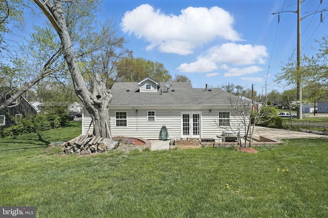 back of house featuring entry steps, a patio, roof with shingles, and a lawn