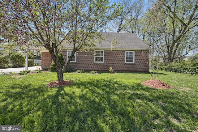 view of side of property with a yard, a shingled roof, and brick siding