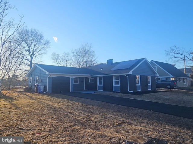 single story home with driveway, a chimney, and an attached garage