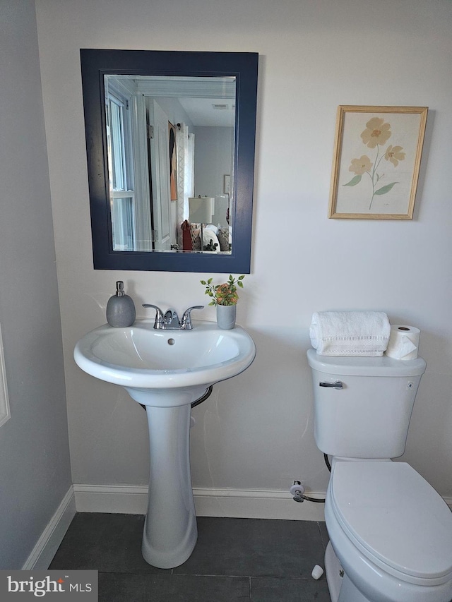 bathroom with toilet, tile patterned flooring, and baseboards