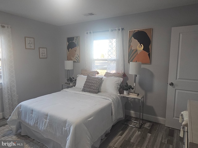 bedroom with dark wood-style floors, visible vents, and baseboards