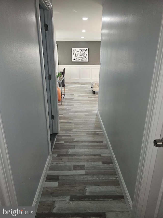 corridor with a wainscoted wall, dark wood finished floors, recessed lighting, a decorative wall, and baseboards