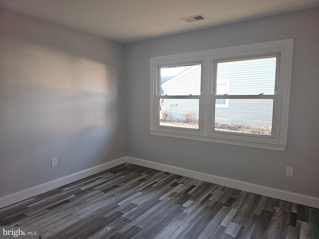 spare room featuring visible vents, dark wood finished floors, and baseboards