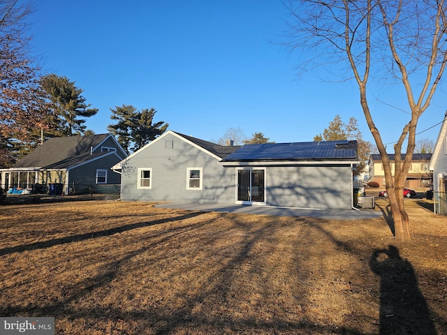 rear view of property featuring a patio area, fence, and roof mounted solar panels