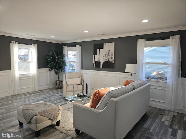 living area featuring wainscoting, visible vents, crown molding, and wood finished floors