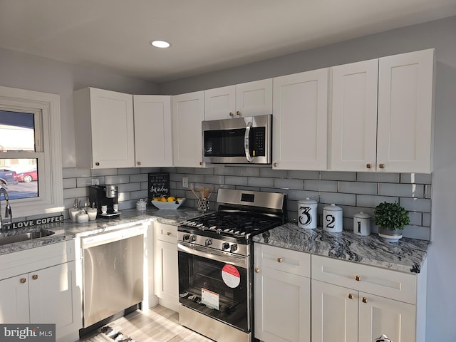 kitchen with light stone countertops, white cabinetry, stainless steel appliances, and decorative backsplash