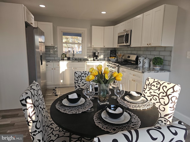 kitchen featuring light stone countertops, white cabinetry, dark wood-style floors, and appliances with stainless steel finishes