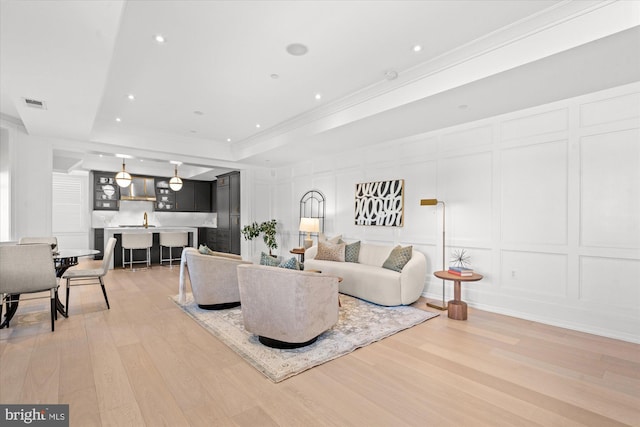 living room featuring light hardwood / wood-style flooring, a tray ceiling, and ornamental molding