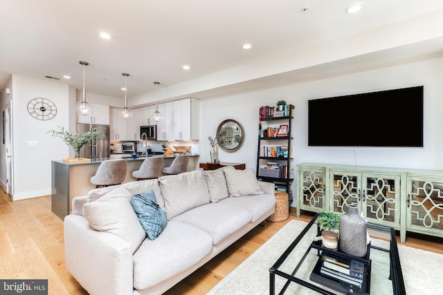 living room featuring light wood-style flooring, baseboards, and recessed lighting