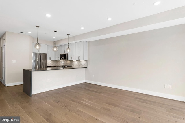 kitchen with pendant lighting, stainless steel appliances, dark countertops, white cabinets, and a peninsula