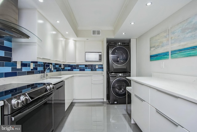 laundry area featuring visible vents, stacked washer and clothes dryer, a sink, tile patterned flooring, and laundry area