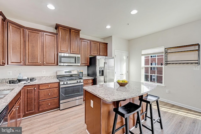 kitchen featuring light hardwood / wood-style floors, a center island, stainless steel appliances, and light stone counters