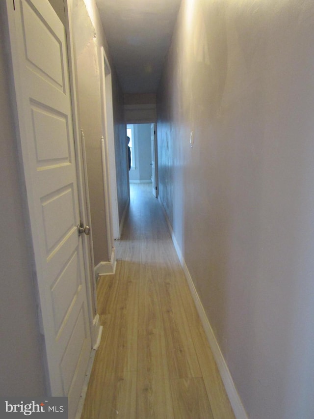 corridor featuring light wood-type flooring and baseboards